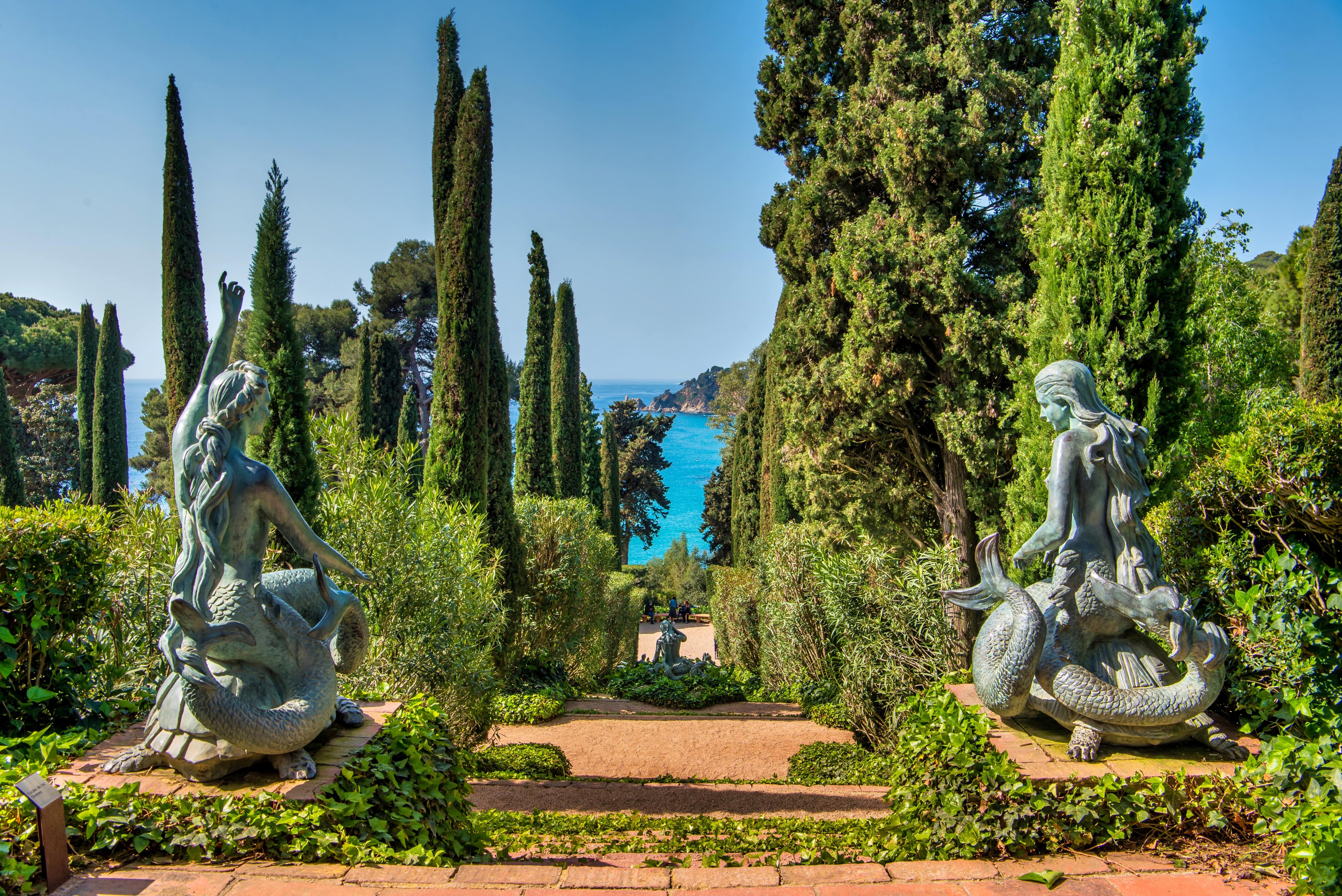 Imatge de les escultures de les sirenes dels Jardins de Santa Clotilde des de la part  posterior, amb vistes al mar de fons, a Lloret de Mar